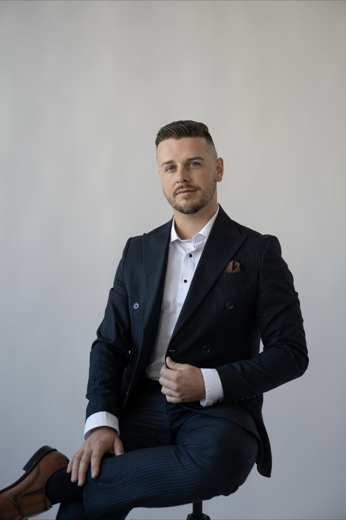 Király Dominik sediaci v tmavomodrom obleku, celý portrét